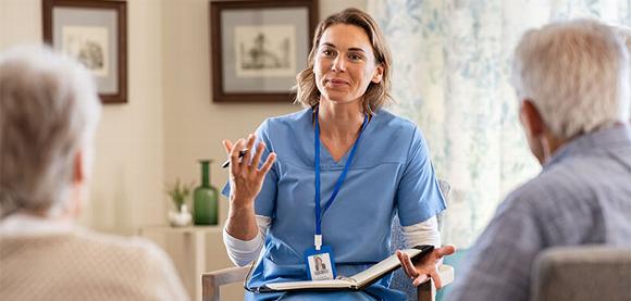 carer chatting with older couple in home assessment