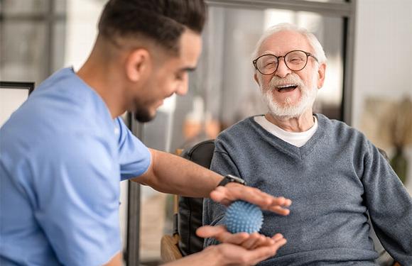 Male carer helping older man with physiotherapy
