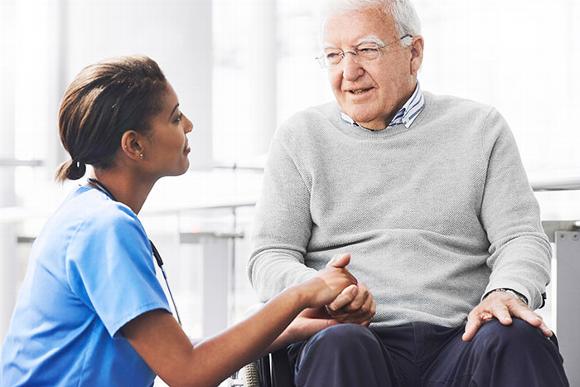 Care worker crouched down talking with older man